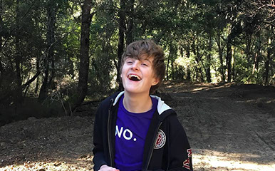 A student laughing on a forest trail